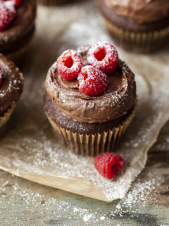 A tender gluten free chocolate cupcake with sourcream frosting and raspberries