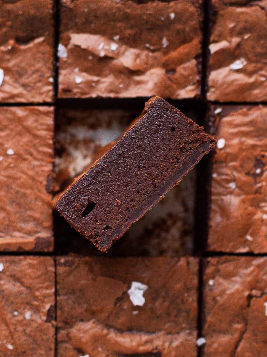 A piece of fudge brownie standing on its side to show the fudgy interior