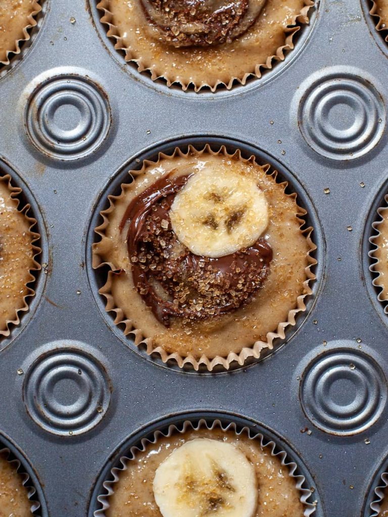 Batter for the muffins in the tin topped with Nutella and Bananas