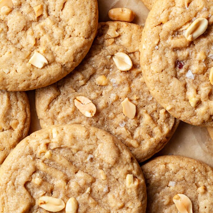closeup of gluten free peanut butter cookies on a brown paper topped with peanuts and salt