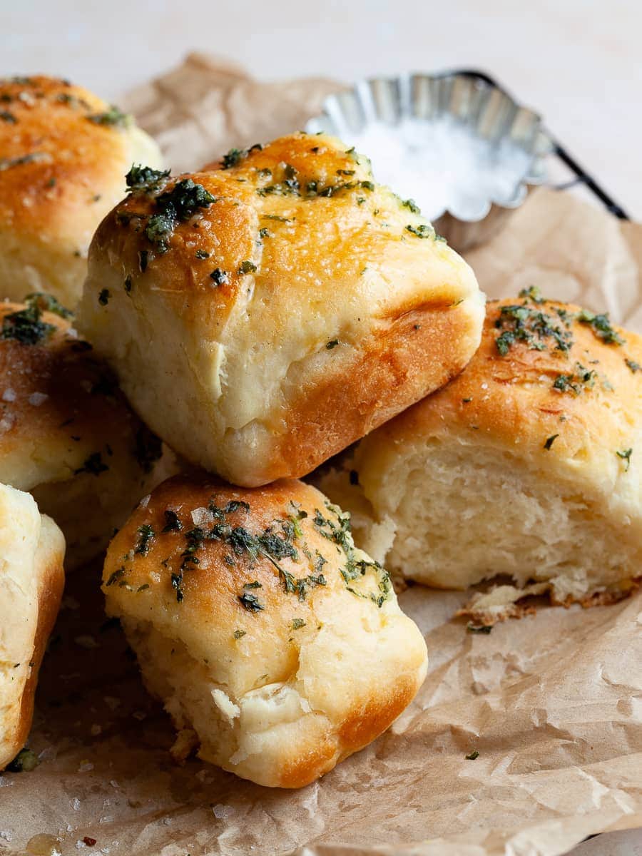 a pile of fresh baked gluten free dinner rolls topped with garlic butter