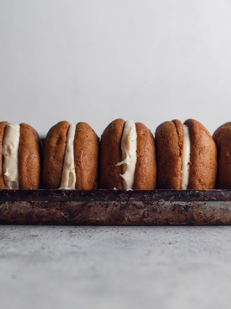 Gluten Free Gingerbread Whoopie Pies are two perfectly spiced, soft gingerbread cookies sandwiched together with a luscious brown sugar frosting. The cake-like cookies are full of warm winter spices with a melt-in-your-mouth texture.