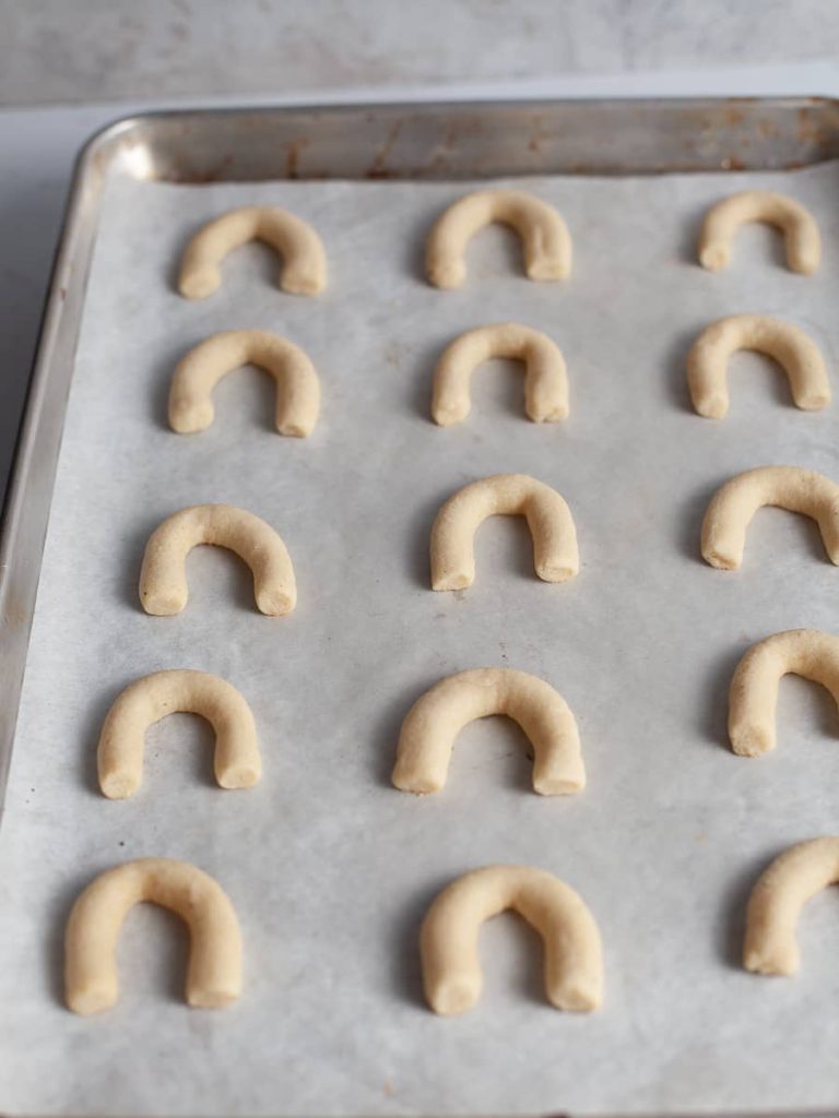 baked crescent cookies lined up on sheet tray