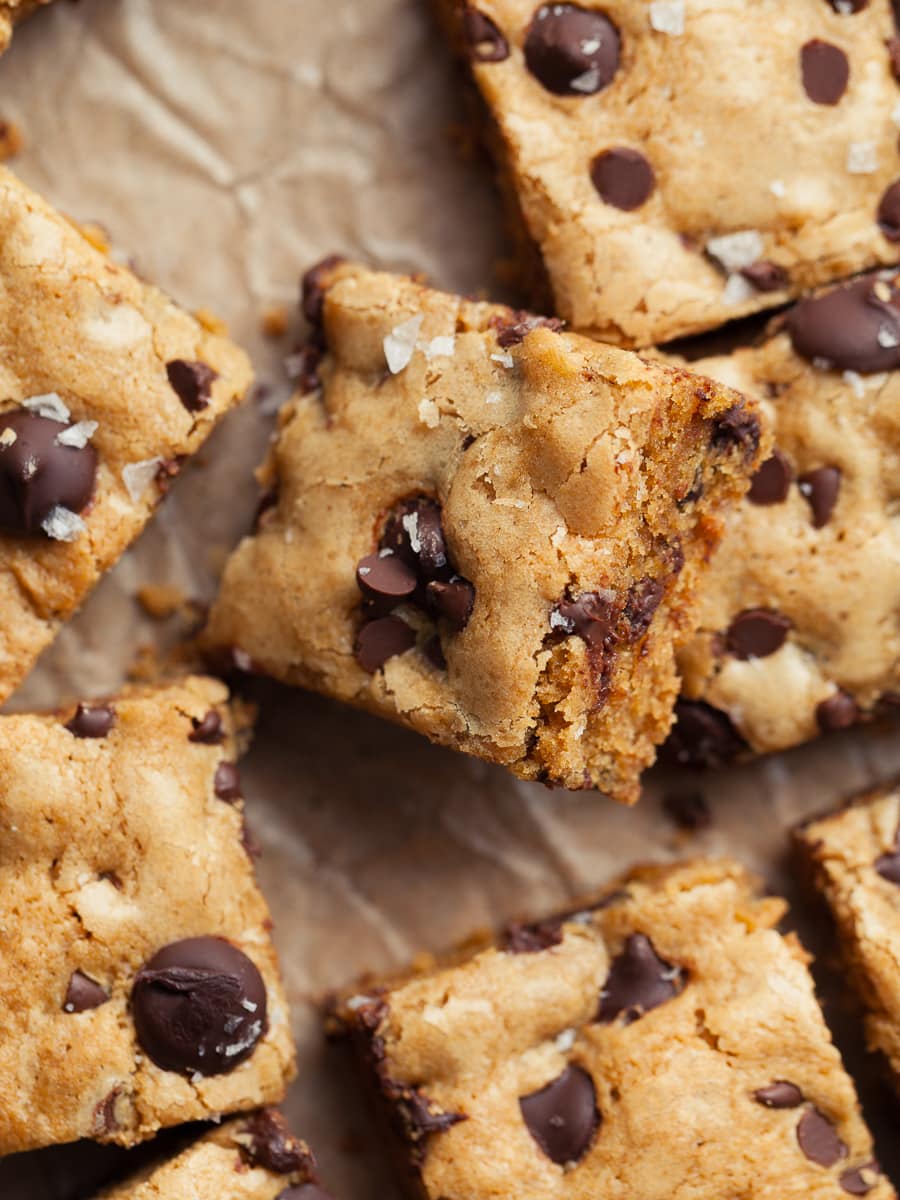 rich and buttery gluten free blondies topped with chocolate chips and flaky sea salt on brown parchment paper