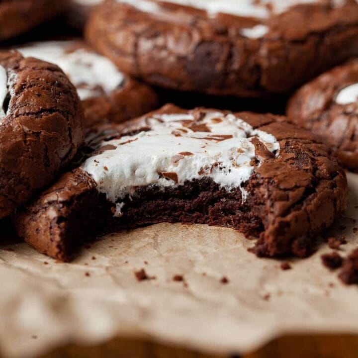 gluten free hot cocoa cookies with swirls of marshmallow fluff on brown parchment paper