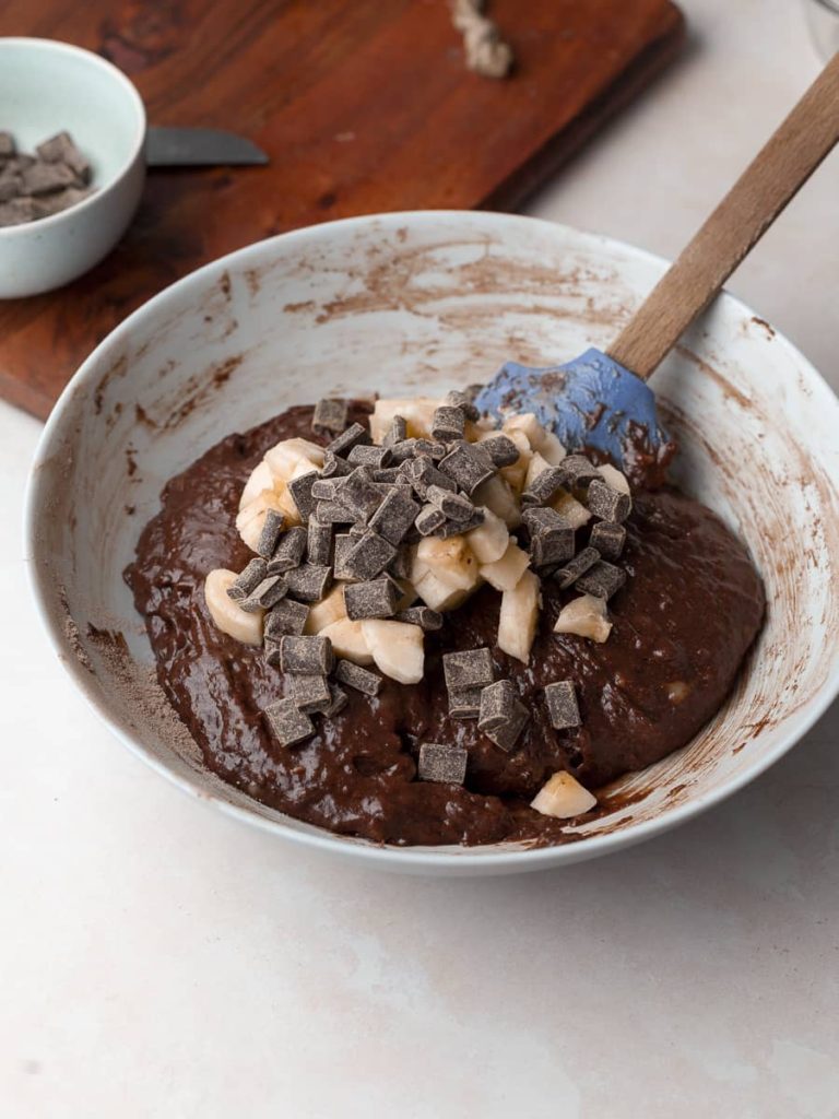 chocolate banana muffin batter in bowl with chopped bananas and chocolate chunks