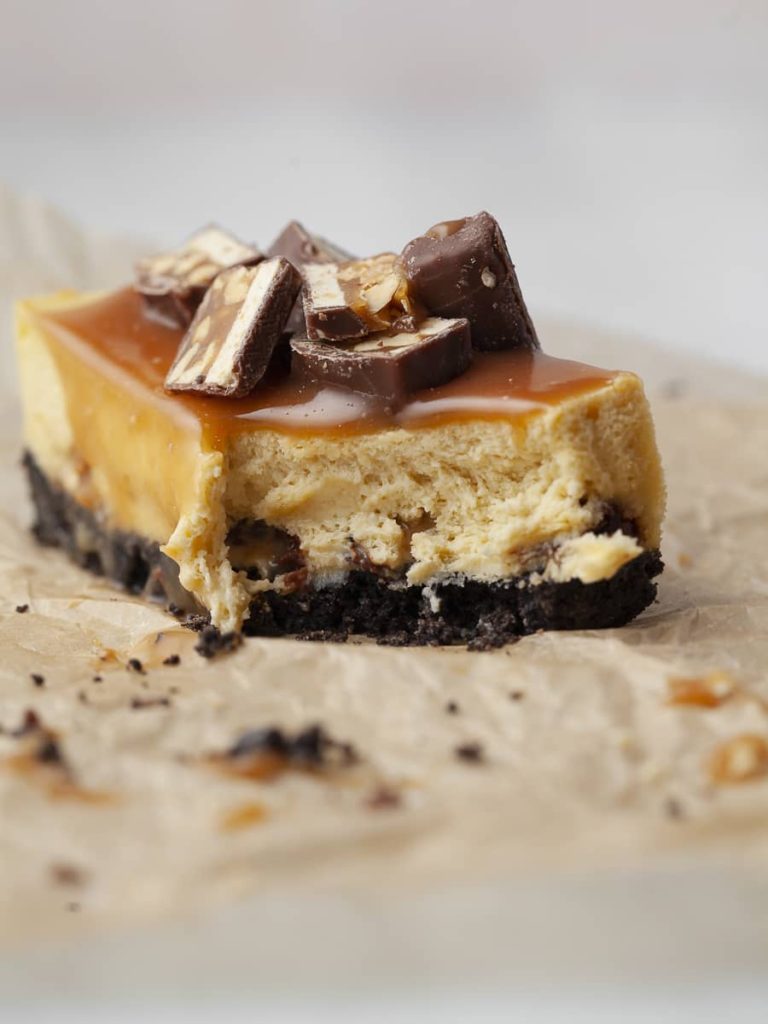 the best snickers cheesecake topped with salted caramel and chopped up snickers
