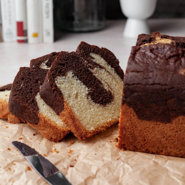 sliced gluten free marble cake on parchment paper with a knife