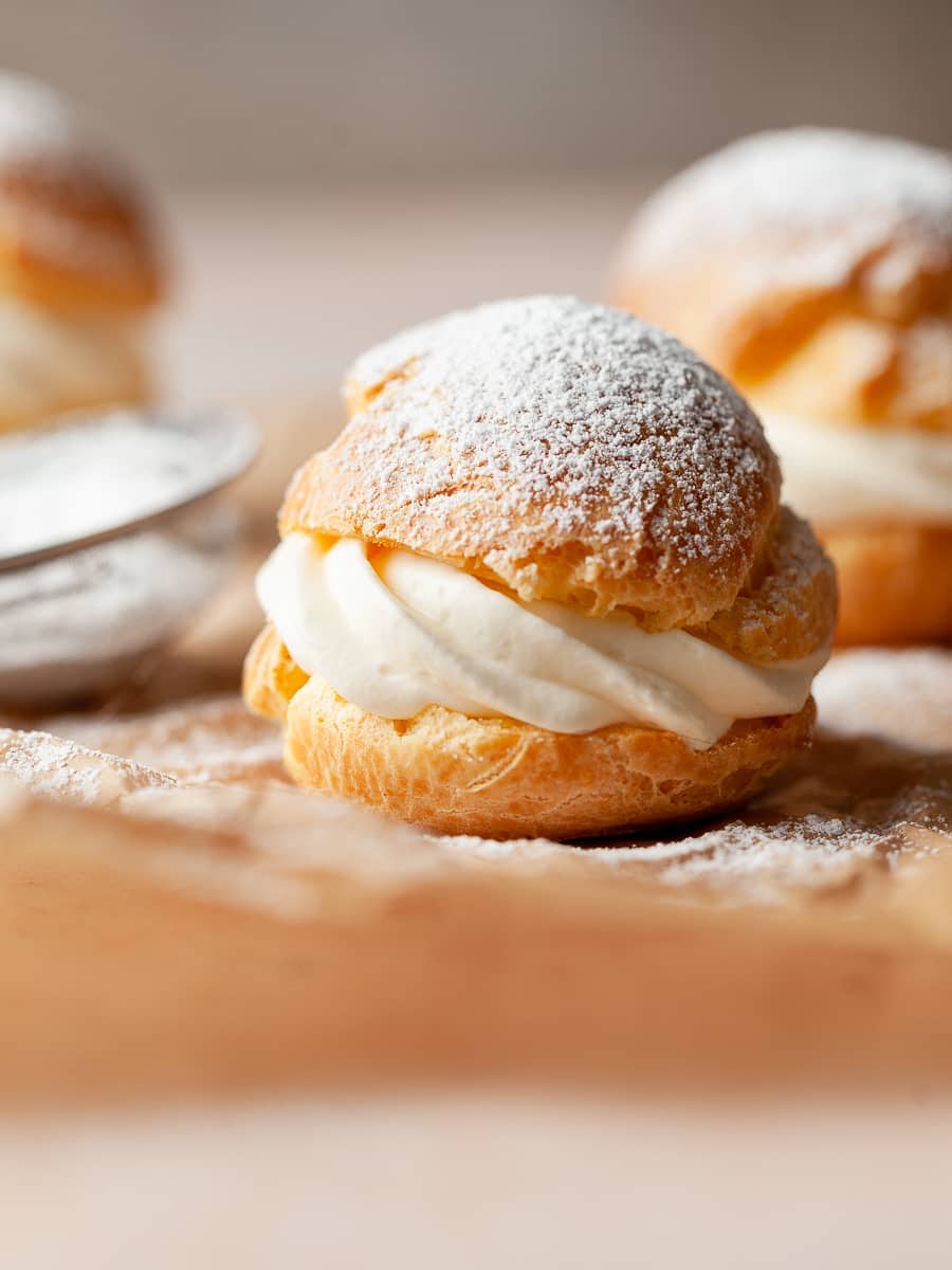 a gluten free cream puff filled with whipped cream and topped with powdered sugar