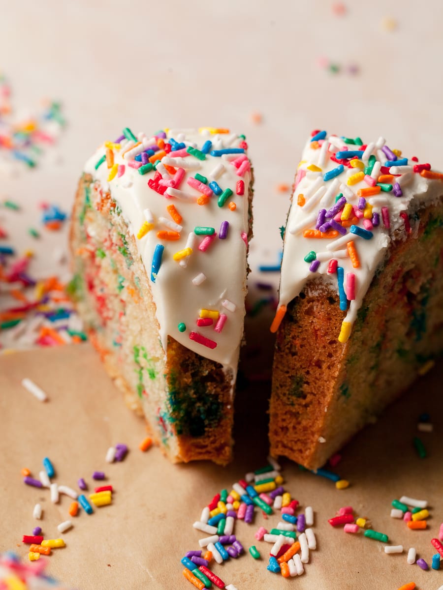 slices of gluten free funfetti cake with cream cheese frosting and jimmie sprinkles