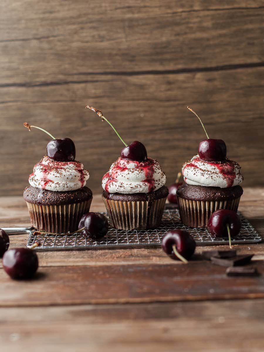 gluten free black forest cupcake with whipped cream frosting. topped with shaved chocolate and a fresh cherry