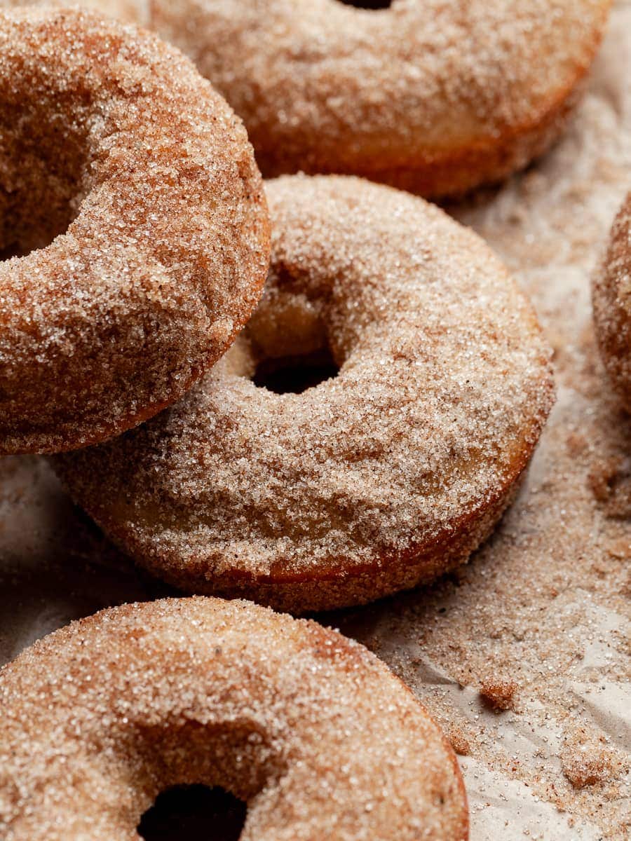 A close up of gluten free apple cider donuts covered with cinnamon sugar