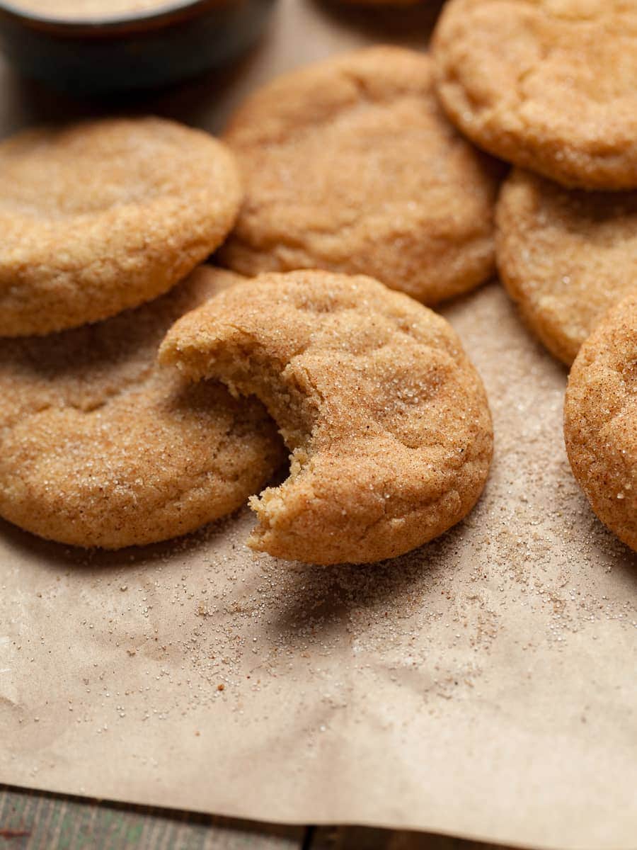 gluten free brown butter snickerdoodle with a bite taken out on brown parchment paper