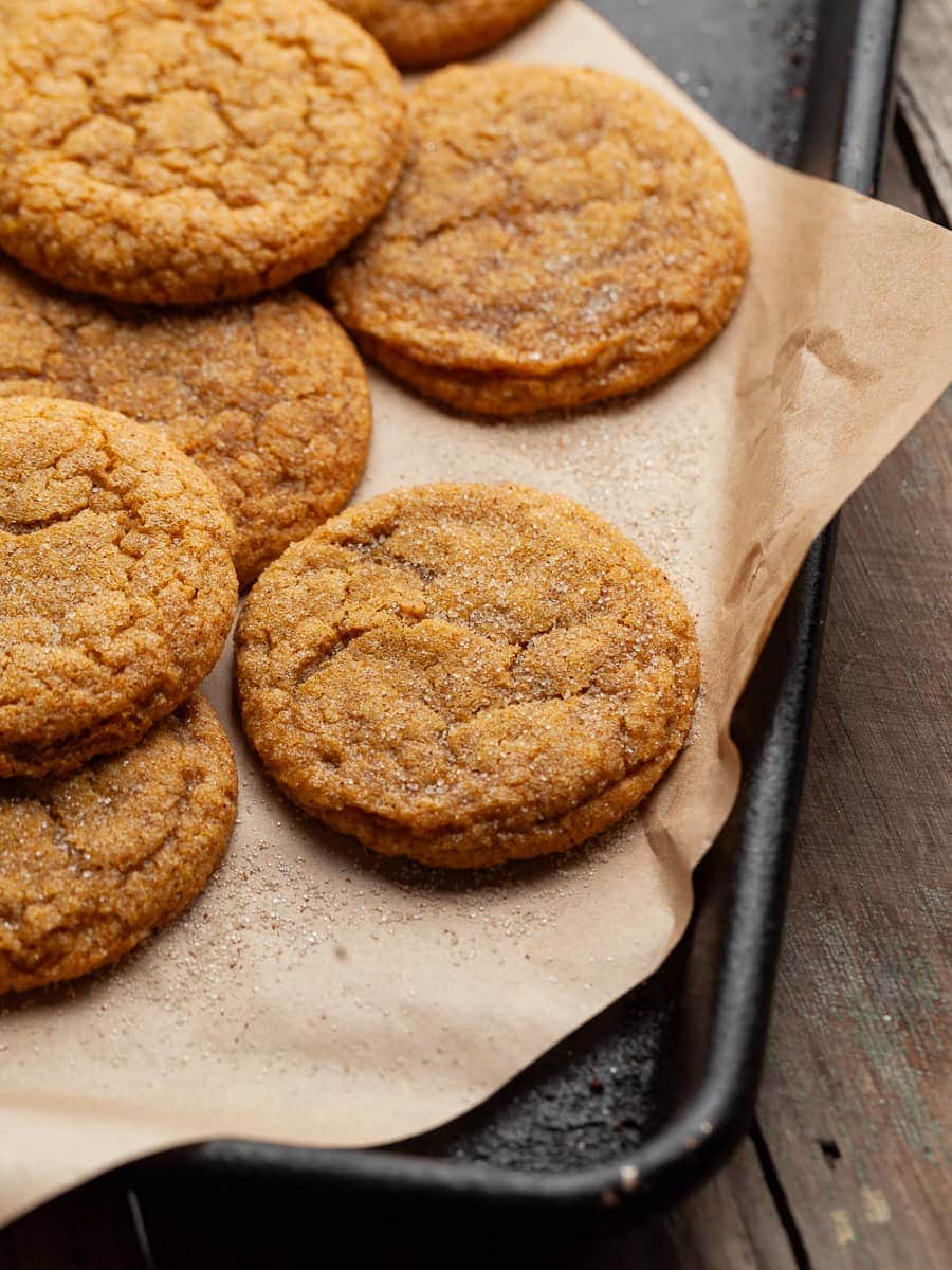 gluten free pumpkin cookies on a black sheet tray and brown parchment paper