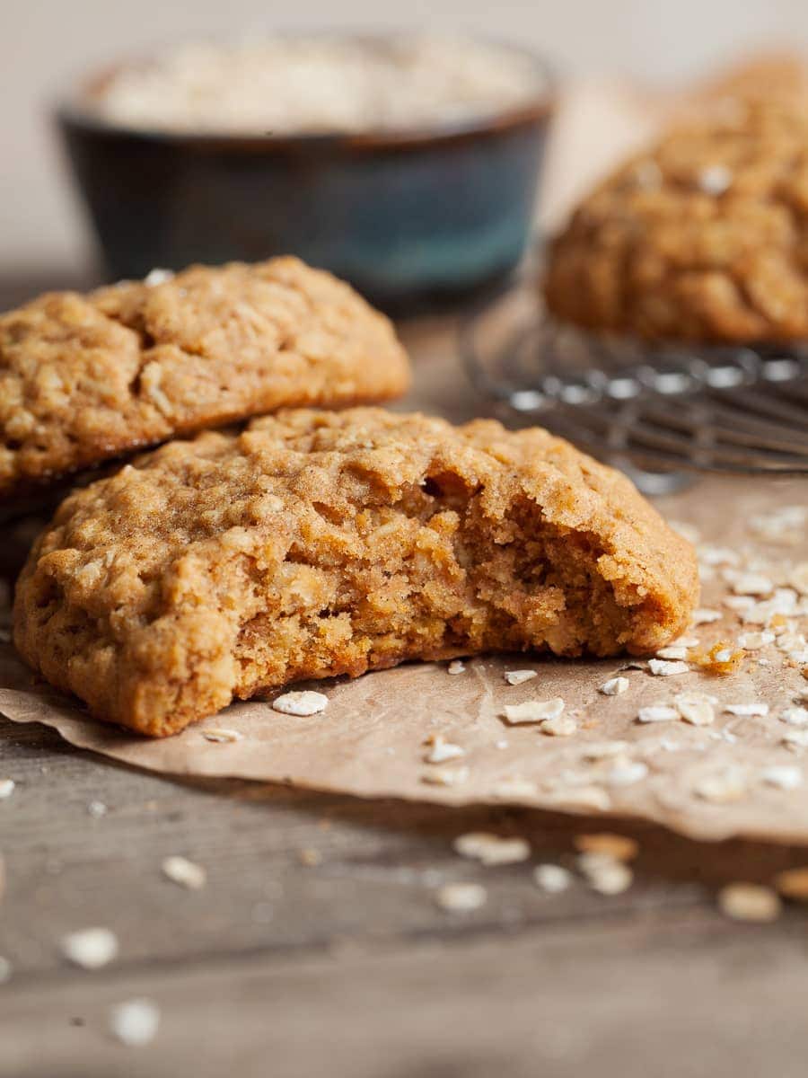 Gluten Free Pumpkin Oatmeal Cookie with a bite taken out on a brown parchment paper topped with instant oats