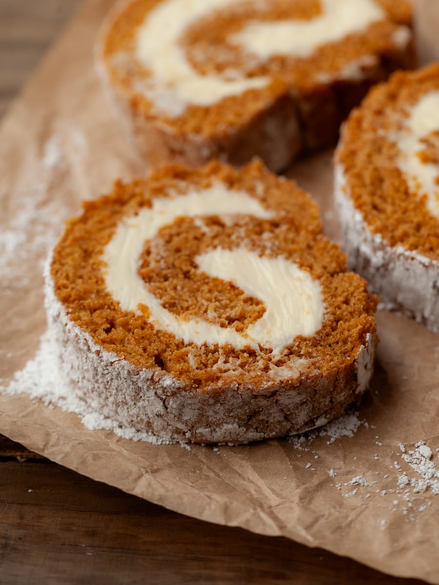 a sliced gluten free pumpkin cake roll on a brown parchment paper