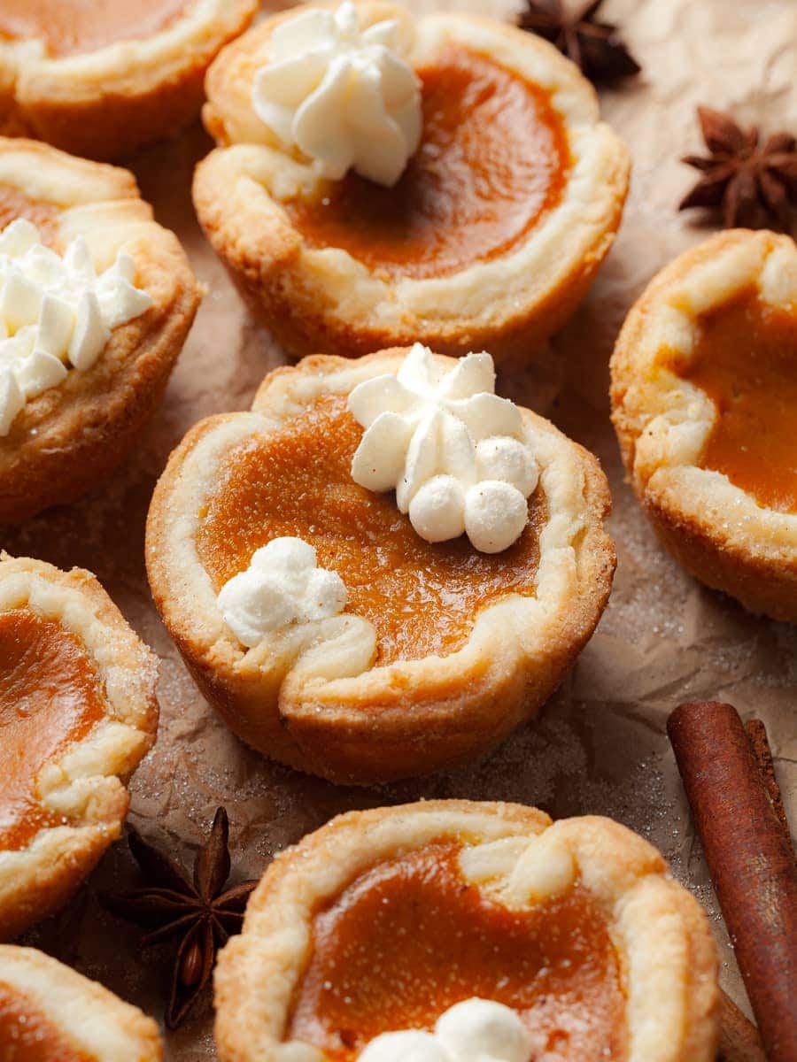 Gluten Free Mini Pumpkin Pies with whipped cream on brown parchment paper