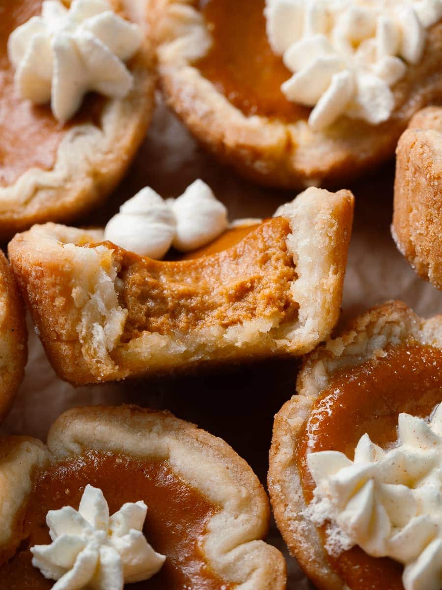 Gluten Free Mini Pumpkin Pies with whipped cream on brown parchment paper