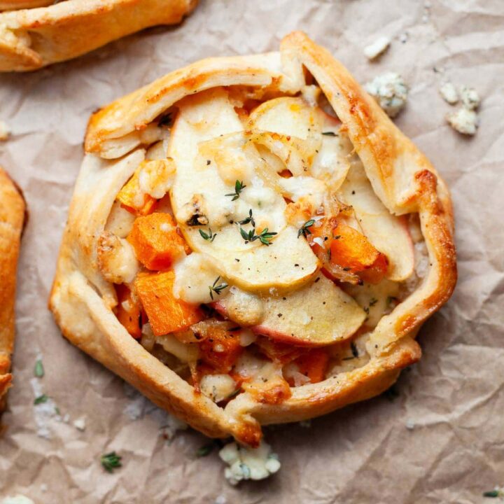 a gluten free savory galette with butternut squash, apples, sweet onions and blue cheese on brown parchment paper