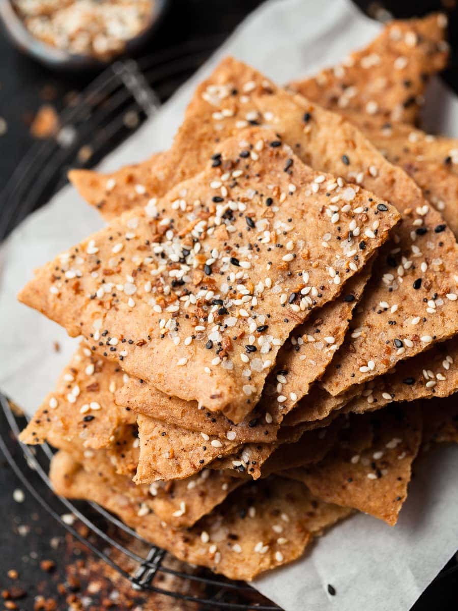 a stack of gluten free sourdough discard crackers on parchment paper and a sheet tray