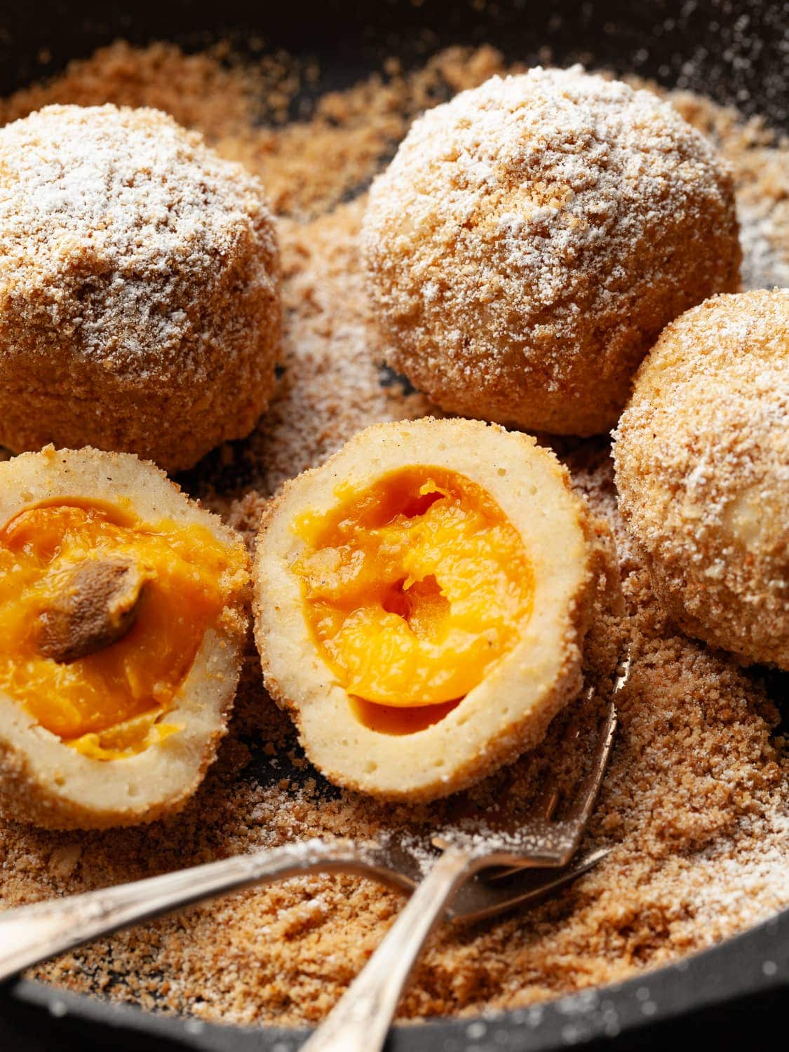 gluten free austrian apricot dumplings covered with bread crumbs and powdered sugar in a cast iron pan