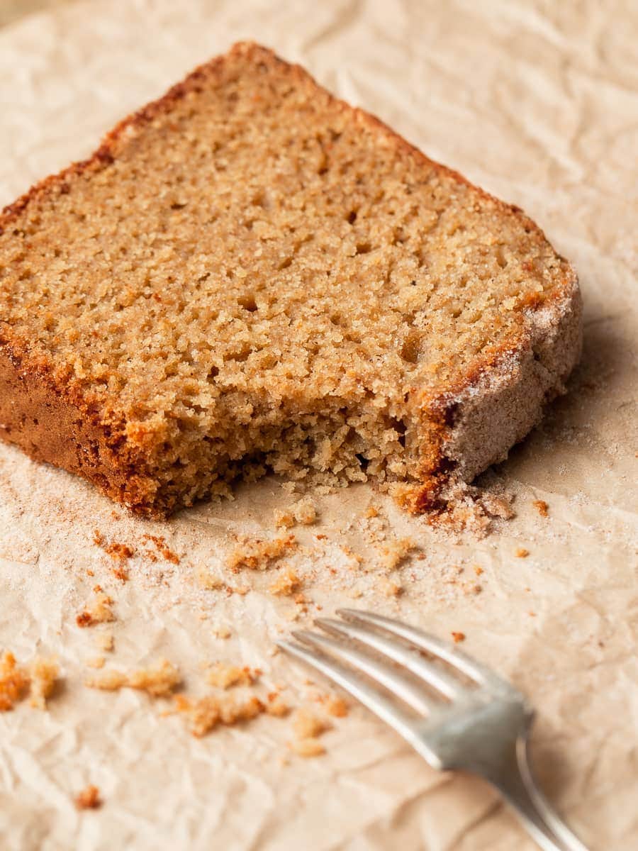 a slice of apple cider donut bread on parchment paper, a piece broken off