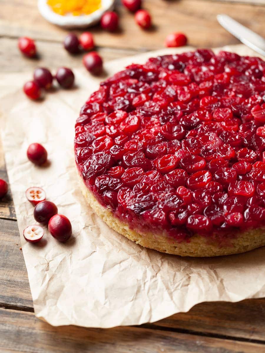 a gluten free cranberry upside down cake with some fresh cranberries scattered around it