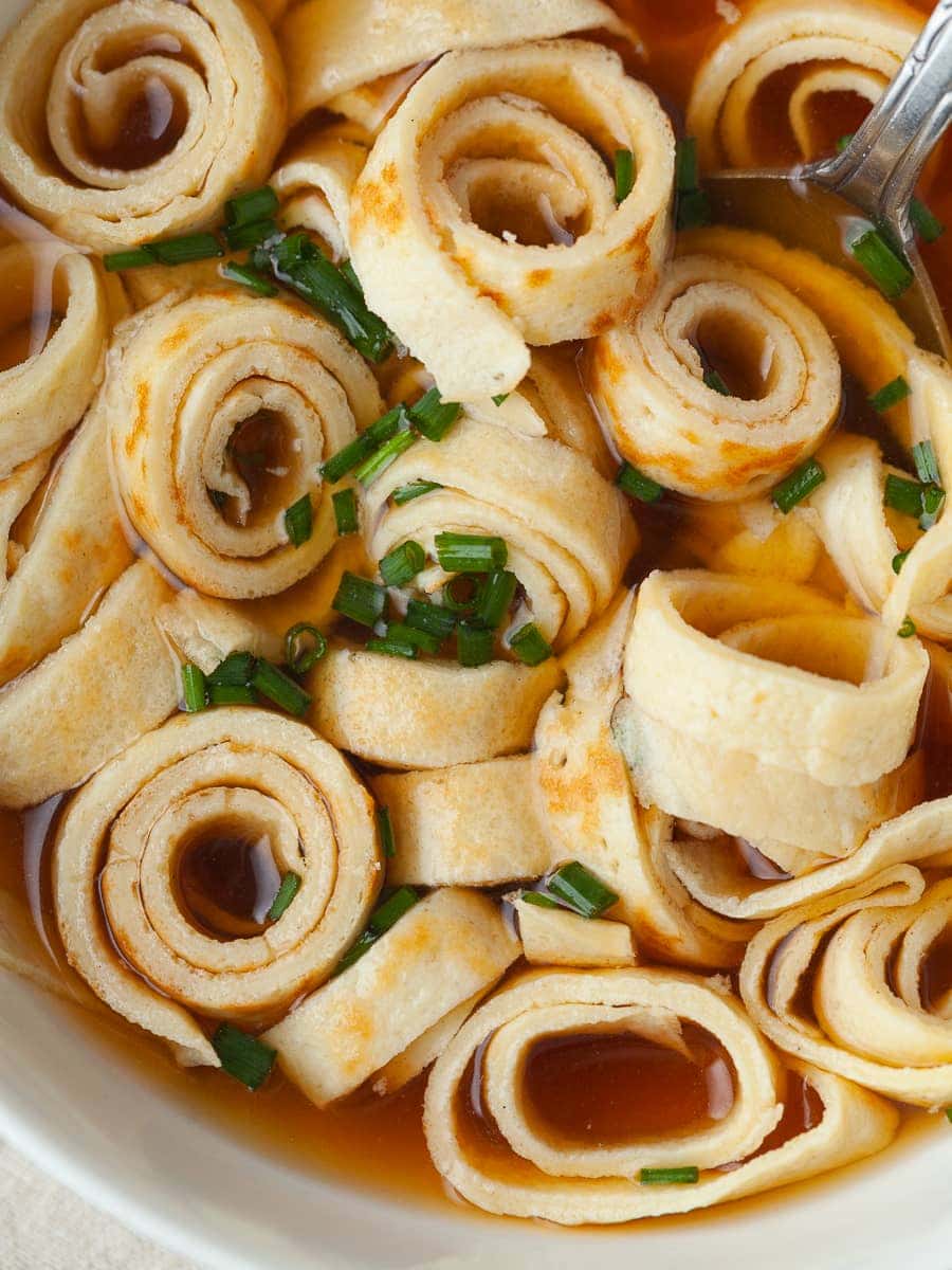 a close up of gluten free frittaten in beef broth and topped fresh chives