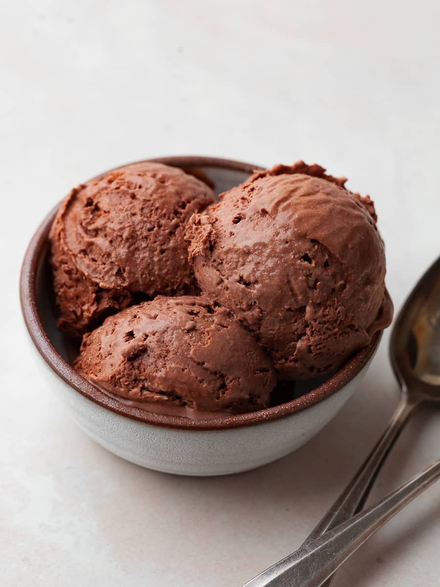 a bowl of no churn chocolate ice cream in a small bowl with two spoons