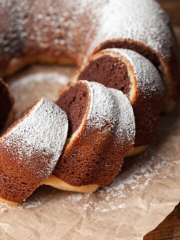 slices of gluten free whipped bundt cake topped with powdered sugar on parchment paper