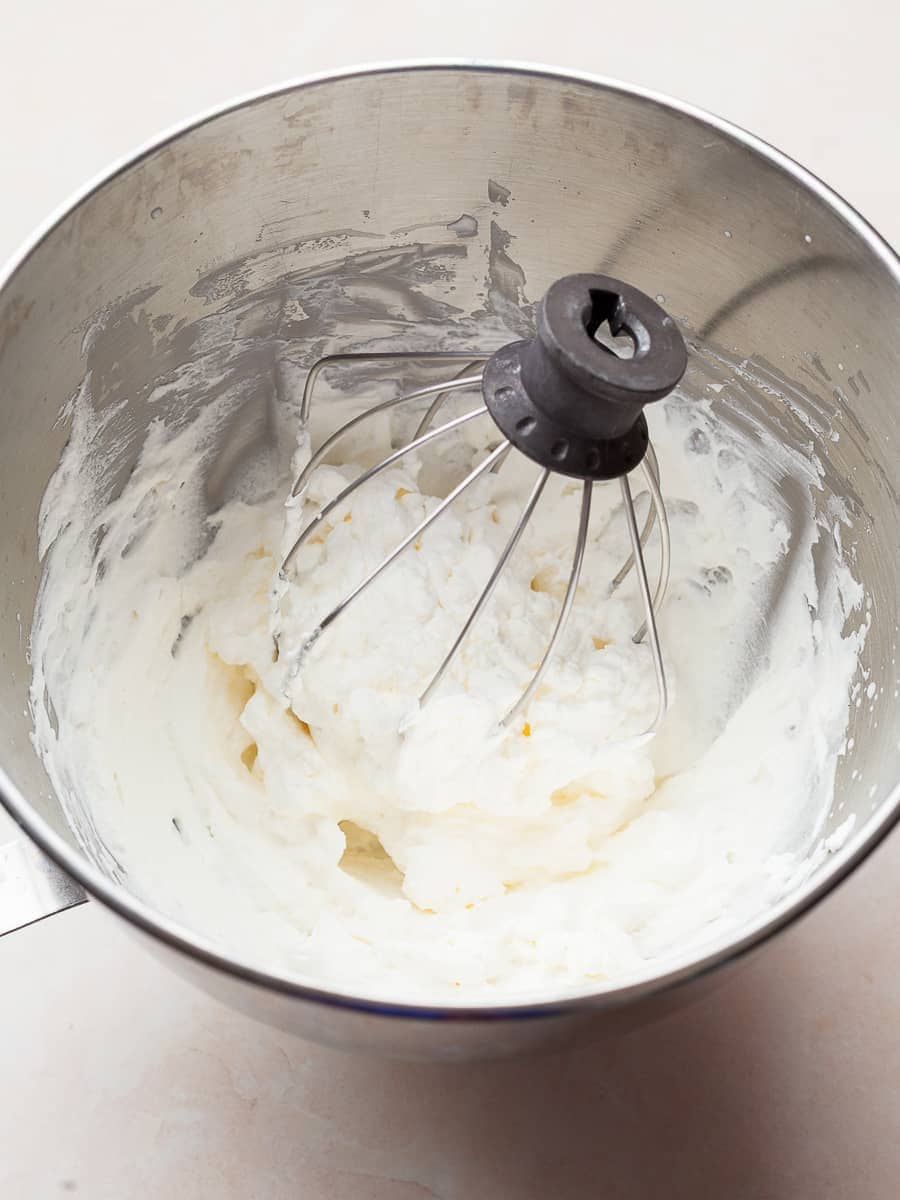 bowl of stand mixer with whisk and whipped cream
