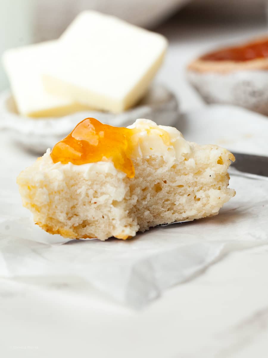 a piece of gluten free drop biscuit topped with butter and apricot jam