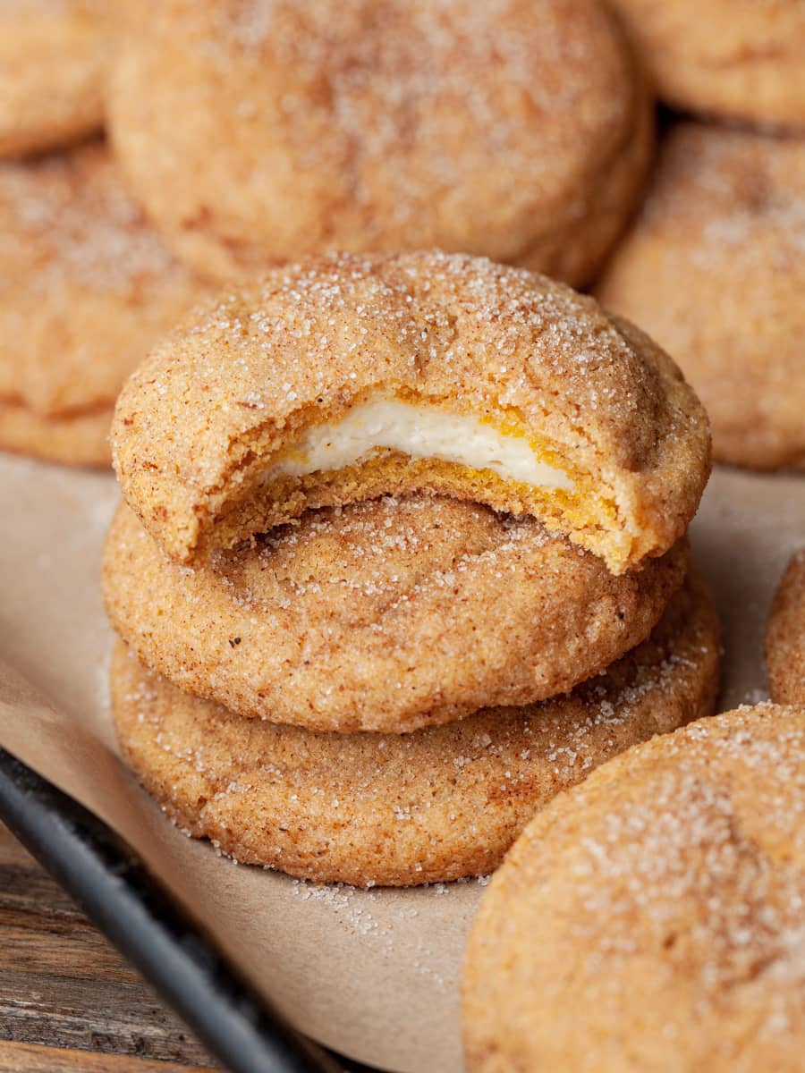 gluten free pumpkin cheesecake snickerdoodles on a baking tray. with the cheesecake filling showing in one cookie