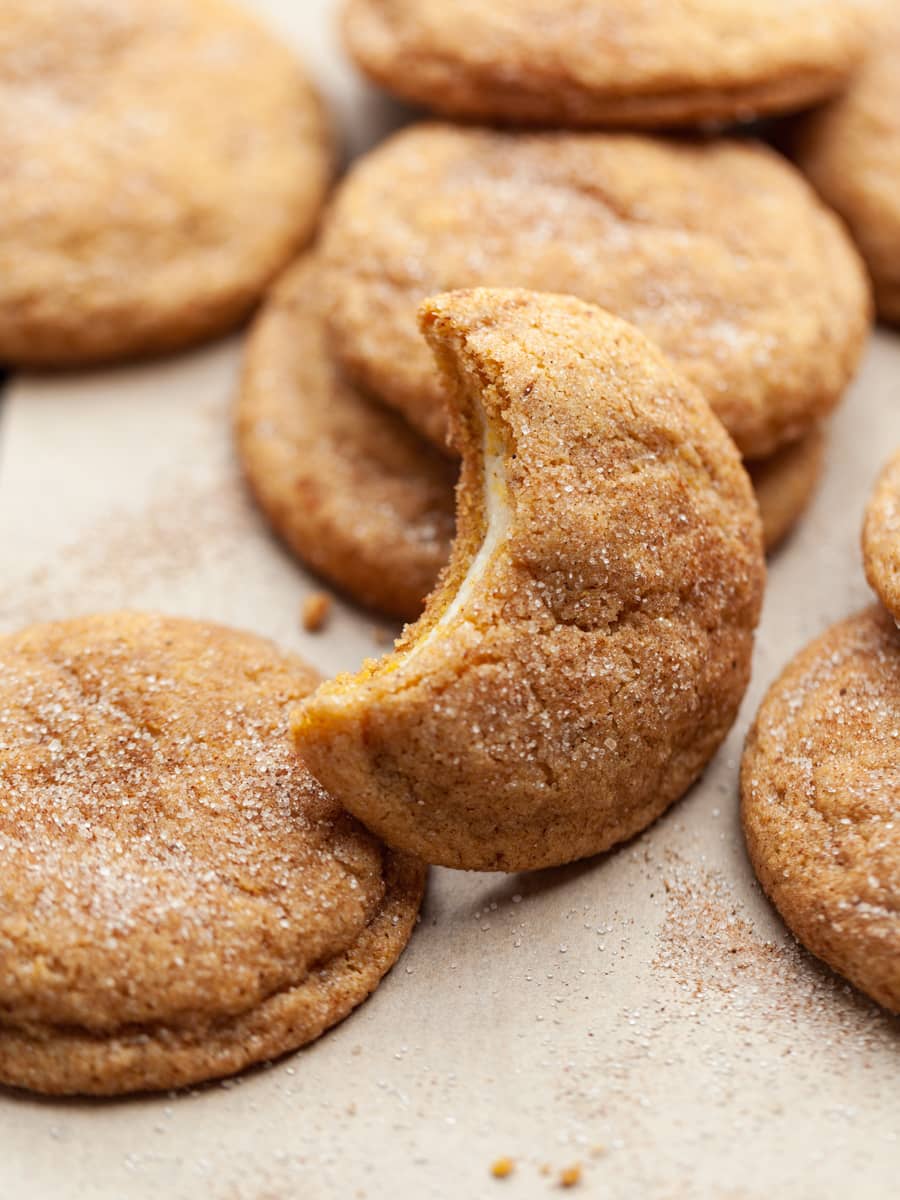 gluten free pumpkin cheesecake snickerdoodles on a baking tray. with the cheesecake filling showing in one cookie